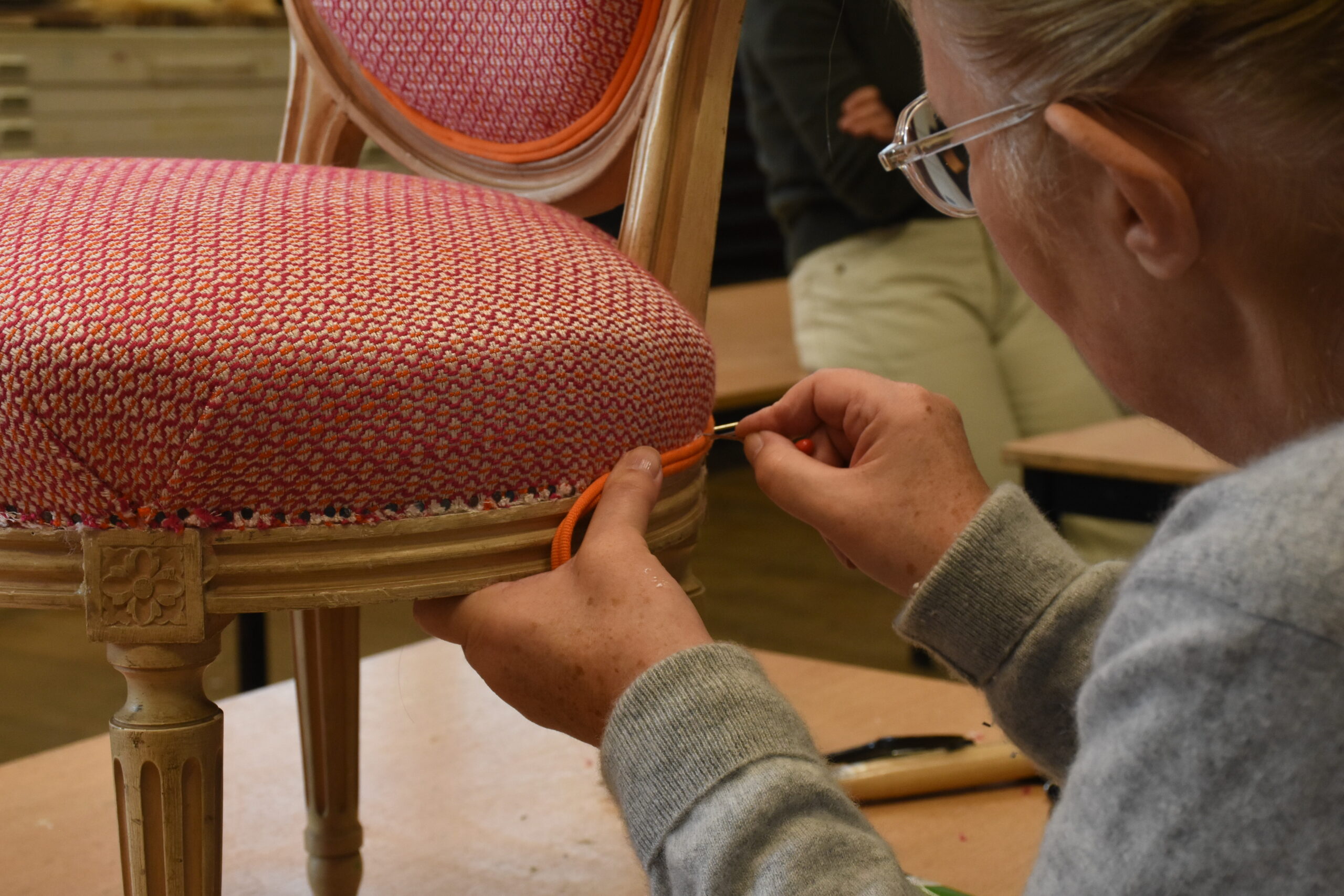 Une dame entrain de retaper un siège lors du cours de tapisserie
