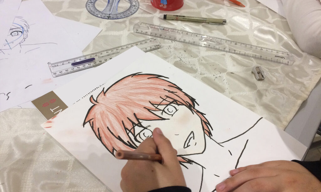 Photo de la main d'un enfant qui dessine un personnage de manga